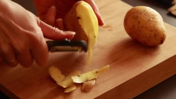  woman hands peeling potatoes on wooden board - Footage, Video