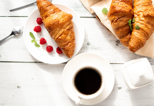 Kuppi kahvia, croissantteja ja marjoja. valkoisella puulla. Aamiainen. Huomenta.. - Valokuva, kuva