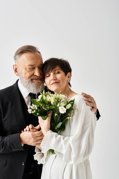 Braut und Bräutigam mittleren Alters im Brautkleid feiern ihren besonderen Tag im Studio nebeneinander. - Foto, Bild