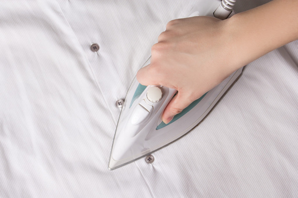 modern iron in female hand ironing cotton shirt - Photo, Image