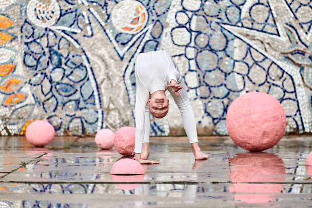 Szabadtéri tánc fiatal balerina lány alopecia fehér futurisztikus öltöny műanyag és rugalmas mozgások között rózsaszín gömbök elvont mozaik szovjet háttérrel, szimbolizálja önkifejezés - Fotó, kép