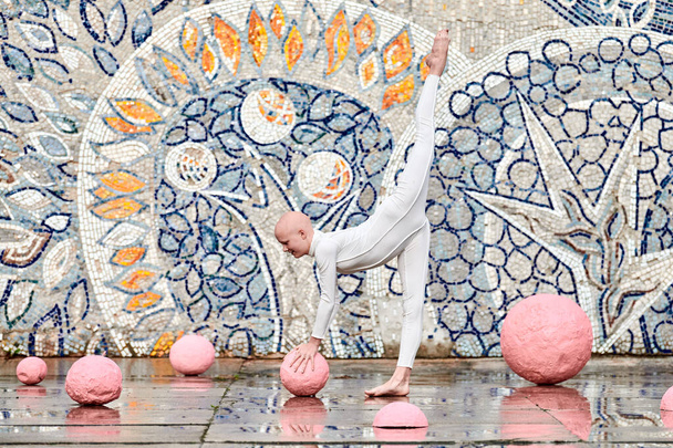 Dança ao ar livre da jovem bailarina menina com alopecia em terno futurista branco com movimentos plásticos e flexíveis entre esferas rosa no mosaico abstrato fundo soviético, simboliza a auto-expressão - Foto, Imagem