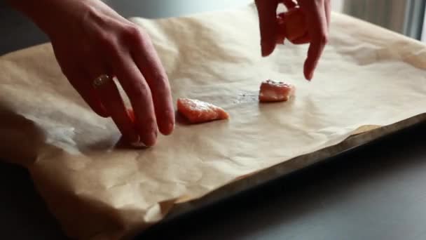 Primer plano de filetes crudos de salmón fresco cortados en cubos y dispuestos en papel pergamino en una bandeja, listos para cocinar, mostrando su calidad y frescura - Imágenes, Vídeo
