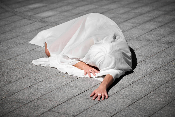 Жінка-виконавець, вкрита білим шовковим шарфом, граціозно махає, жіночий танцювальний виступ на вуличних плитках створює чуттєве і зворушливе видовище на відкритому повітрі - Фото, зображення