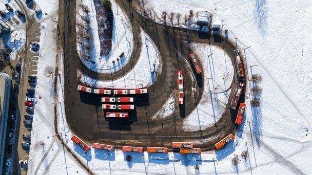 Drone φωτογραφία του μικρού τερματικού σταθμού λεωφορείων με πολλά σταθμευμένα λεωφορεία και τρόλεϊ κατά τη διάρκεια του χειμώνα ηλιόλουστη μέρα - Φωτογραφία, εικόνα