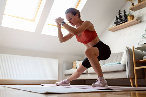 Fitness en casa. Mujer atlética haciendo ejercicio en casa. Estilo de vida deportivo doméstico de personas reales. - Foto, Imagen