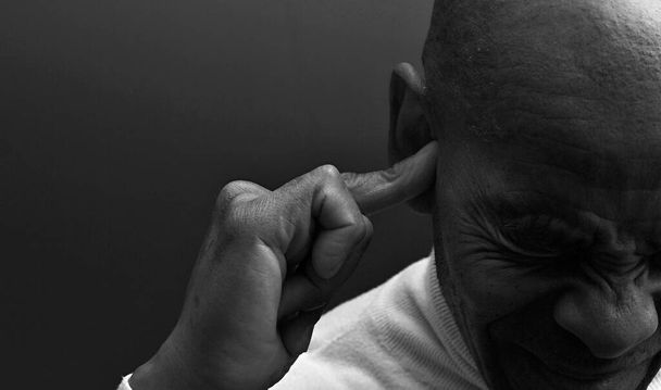 глухий чоловік, який страждає глухотою і втратою слуху на сірому фоні  - Фото, зображення