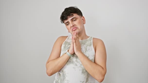Desperate young adult man, standing in prayer, begging with hope, hands clasped, wearing sleeveless t-shirt. distressed expression over isolated white background. - Footage, Video