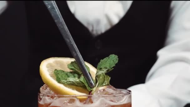 Primo piano di barista decorato a mano Tequila sunrise cocktail con limone a fette. Macro di barista sapiente mano che si prepara per servire cocktail e guarnito con agrumi per rinfrescarsi. Comestibile. - Filmati, video