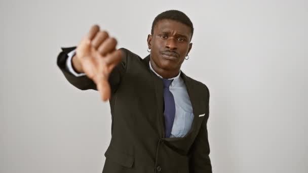Θυμωμένος Αφροαμερικανός με κοστούμι δείχνει τους αντίχειρες προς τα κάτω χειρονομία - αρνητική ή κακή έκφραση, δυστυχισμένος και απομονωμένος σε λευκό φόντο - Πλάνα, βίντεο