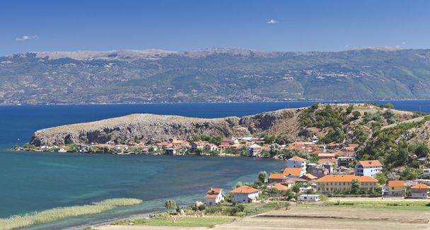 Costa od lago Ohrid con casas cubiertas rojas
 - Foto, imagen