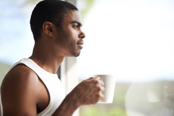 Black man, window and thinking with coffee for morning, start or ambition in dream or vision at home. Face of African male person in wonder or thought with mug or cup of tea for breakfast on mockup. - Photo, Image