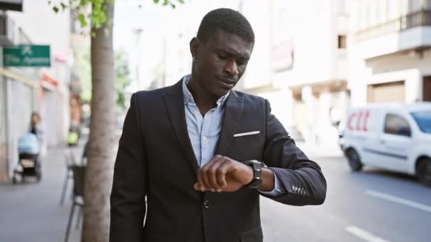 A confident african man in a suit checking his watch on a busy city street - Footage, Video