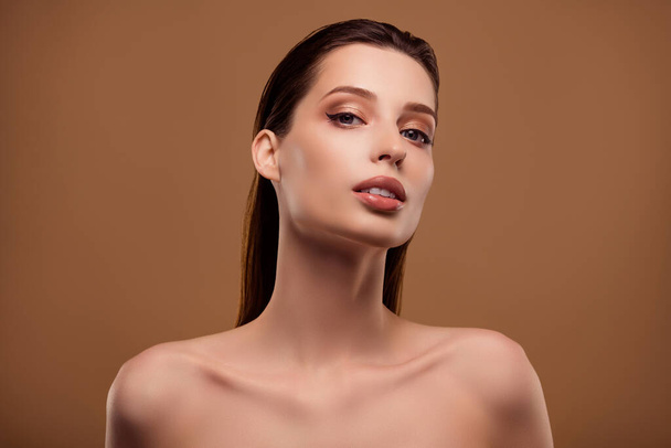 Foto von verführerischen glänzenden Frau nackten Schultern Anwendung Maquillage isoliert beige Hintergrund. - Foto, Bild