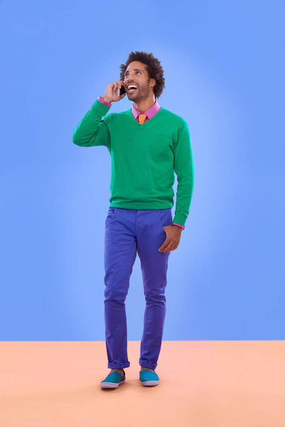 Fashion, black man and phone call in studio for color block in trendy clothes, style and outfit. Male person, stylist and fashionable for season trends with funky, edgy and formal wear in happiness. - Fotoğraf, Görsel