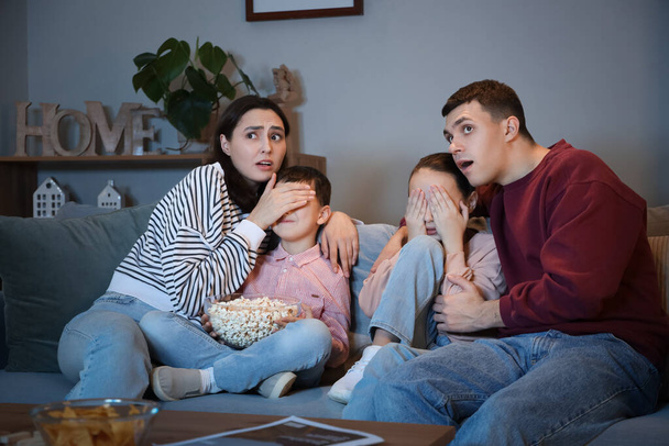 Famille effrayée avec pop-corn regarder la télévision sur le canapé à la maison le soir - Photo, image