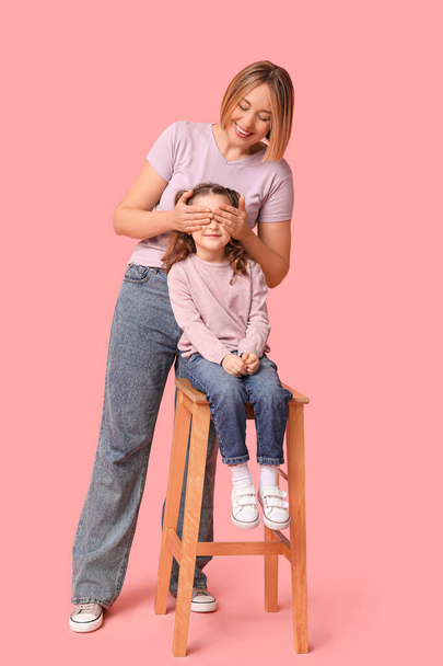 Una niña sentada en la silla y su madre. Día de la Madre - Foto, imagen