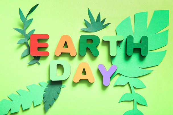Cor letras de madeira com texto TERRA DIA e folhas de papel verde sobre fundo de cor, close-up. Celebração do dia da Terra. - Foto, Imagem