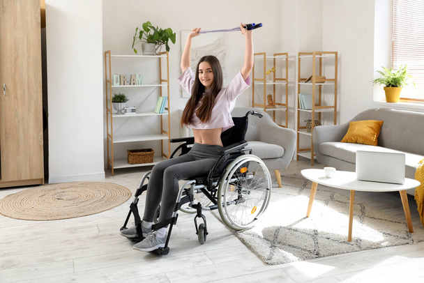 Sporty young woman in wheelchair training with skipping rope at home - Photo, Image