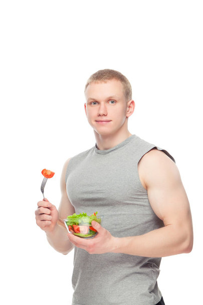 Young happy muscular man eating a salad over white background. - Foto, Bild