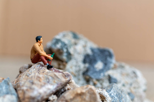 Miniature people, Un jeune homme sirotant de la bière assis sur le rocher - Photo, image