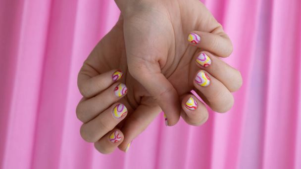 Kobieta manicure ręce, stylowe lato kolorowe paznokcie na różowym tle. Zbliżenie manicure paznokcie żeńskiej ręki. Letni styl koncepcji projektowania paznokci. Zabieg kosmetyczny. - Zdjęcie, obraz