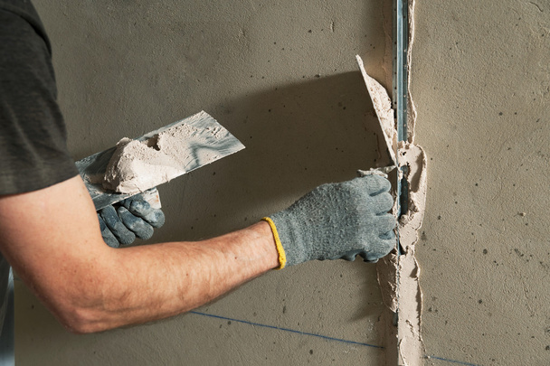 Homem corrige um guia para alinhar as paredes com estuque no futuro
 - Foto, Imagem