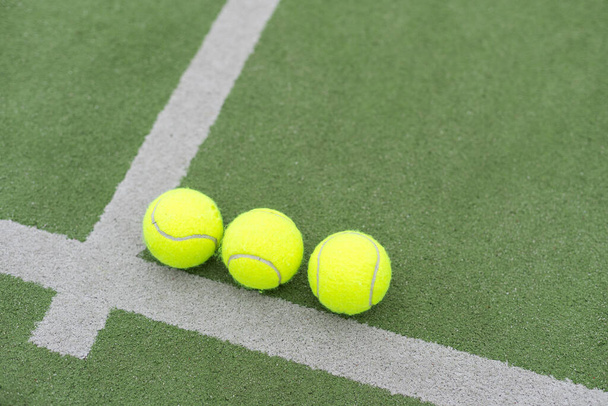 自然の照明で屋外の緑の裁判所のネットの後ろのパネル テニス ラケットの近くの草の芝生の黄色い球. パドルはラケットゲームです. コピースペースを備えたプロスポーツコンセプト。 高品質の写真 - 写真・画像