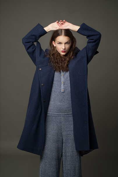 modelo de moda mujer abrigo y sombrero estilo urbano pose sobre fondo de color en estudio
 - Foto, imagen