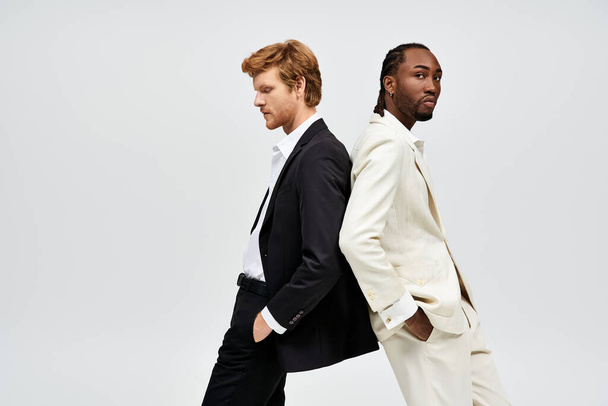 Schöne multikulturelle Männer in eleganten Anzügen posieren Seite an Seite. - Foto, Bild
