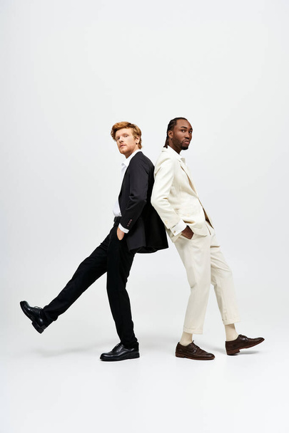 Zwei gutaussehende multikulturelle Männer in Anzügen posieren stilvoll nebeneinander. - Foto, Bild
