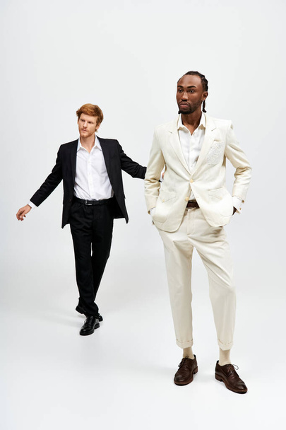 Zwei gutaussehende multikulturelle Männer in schicken Anzügen stehen selbstbewusst nebeneinander. - Foto, Bild