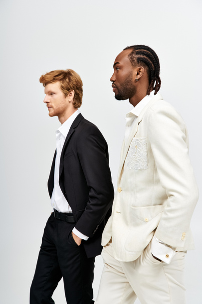 Zwei gutaussehende multikulturelle Männer in schicken Anzügen gehen zusammen spazieren. - Foto, Bild