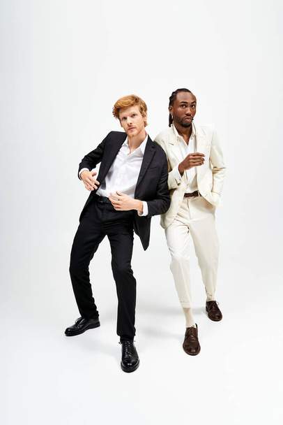 Zwei multikulturelle Männer in stylischen Anzügen posieren selbstbewusst für die Kamera. - Foto, Bild