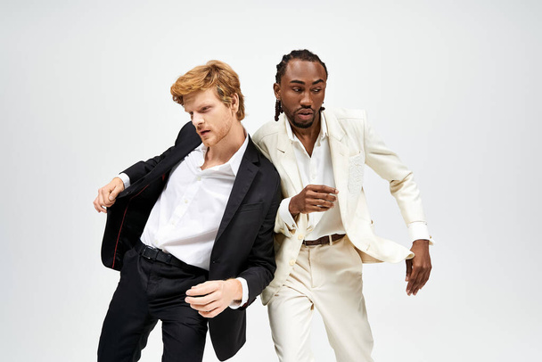 肖像画のためにエレガントにポーズするスタイリッシュなスーツの2人の多文化男性. - 写真・画像