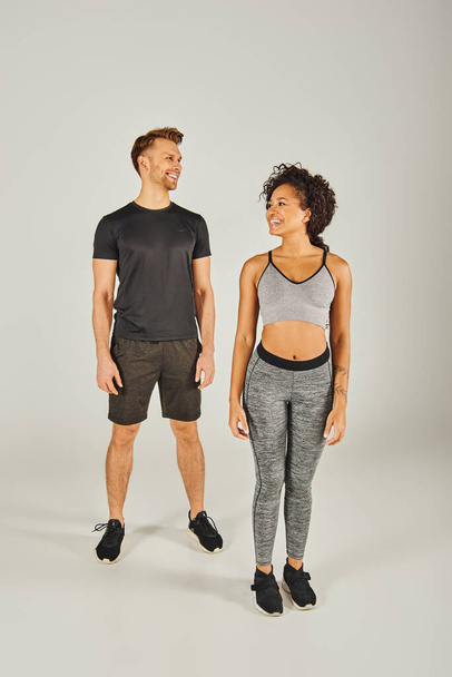 Young interracial sport couple in active wear standing confidently in front of a white background. - Photo, Image