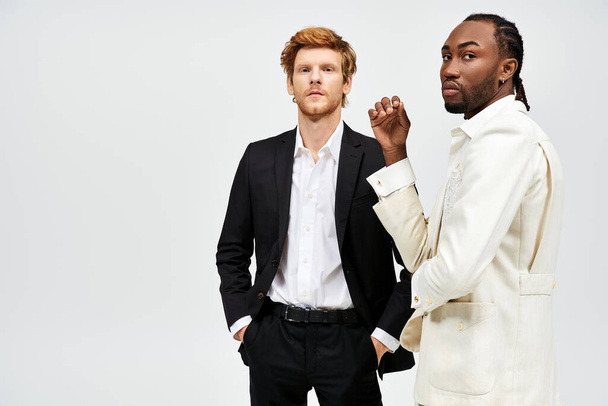 Zwei gutaussehende, multikulturelle Männer in eleganter Kleidung stehen zusammen vor weißem Hintergrund. - Foto, Bild