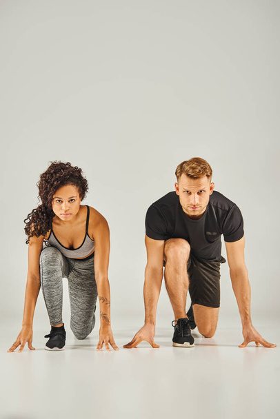Un jeune couple sportif interracial portant une tenue active démontrant une forme de squat parfaite à l'unisson sur fond blanc. - Photo, image