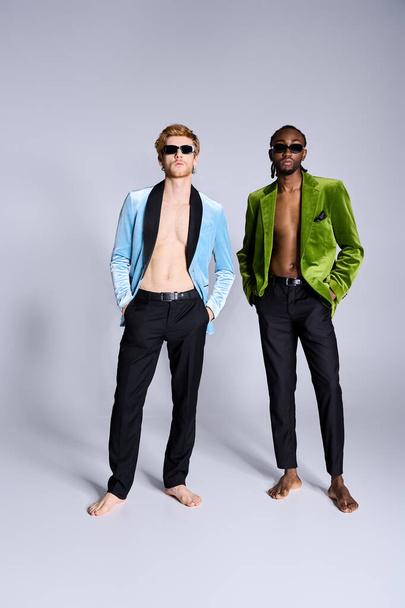 Dva pohlední multikulturní muži s elegantním elegantní elegantní styl stojí bok po boku před šedým pozadím. - Fotografie, Obrázek