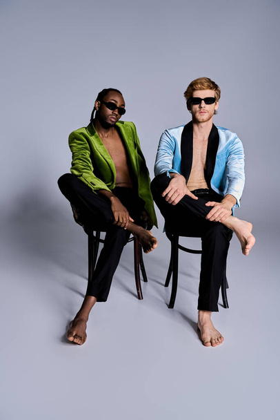 Двоє елегантних мультикультурних чоловіків сидять разом у стильному одязі, займаються розмовою. - Фото, зображення