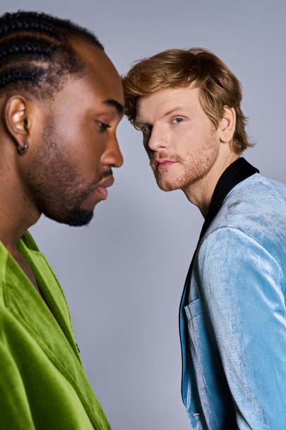 Zwei multikulturelle Männer in schicker Kleidung stehen zusammen und nehmen Blickkontakt auf. - Foto, Bild