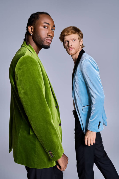 Twee elegante multiculturele mannen die stijlvol poseren voor een grijze achtergrond. - Foto, afbeelding