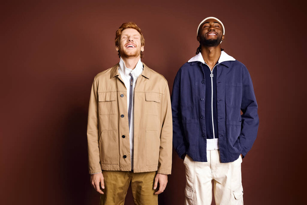 Deux hommes à la mode se tiennent près d'un mur brun. - Photo, image