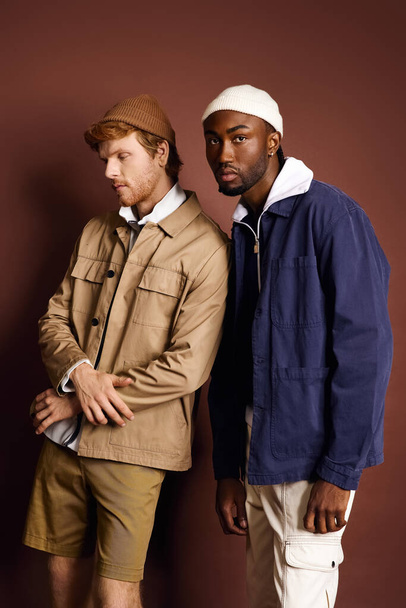 Zwei stylische Männer stehen an einer braunen Wand. - Foto, Bild