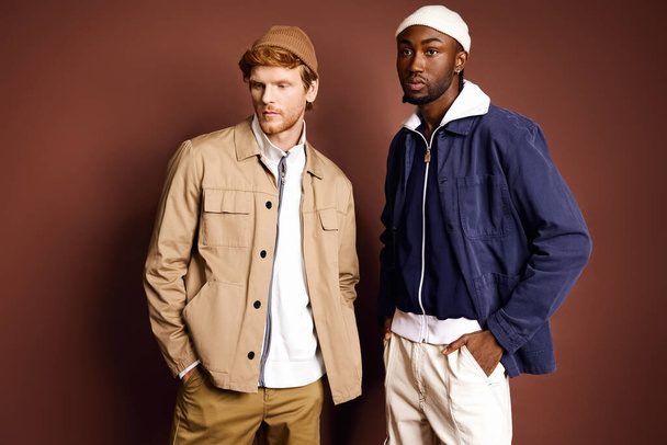 Двоє стильних мультикультурних чоловіків стоять перед коричневою стіною. - Фото, зображення