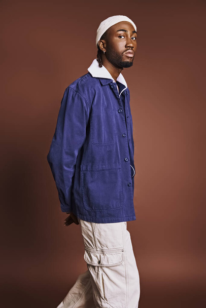Schöner junger afroamerikanischer Mann in blauer Jacke und weißer Hose, selbstbewusst schlendernd. - Foto, Bild