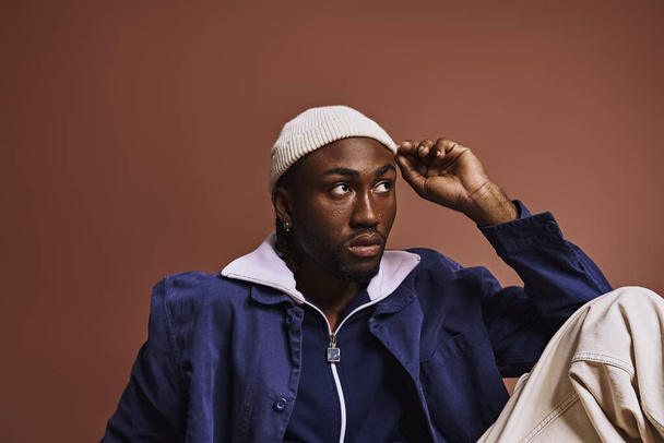Молодий афроамериканський чоловік викриває стиль у синій куртці та білому капелюсі. - Фото, зображення