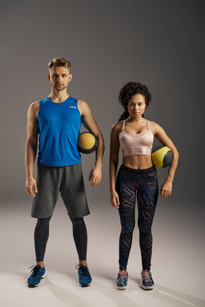 Young multicultural couple in active wear posing confidently for the camera in a studio setting. - Photo, Image