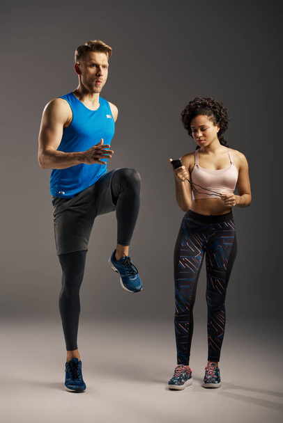 A young multicultural and fit couple stand next to each other in active wear, exuding confidence and strength in a studio setting. - Photo, Image