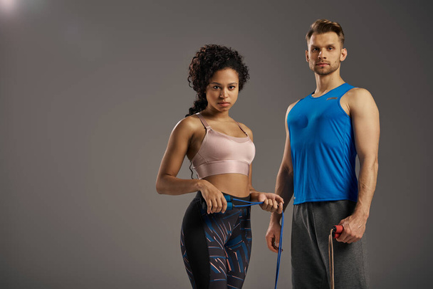Una coppia multiculturale in posa activewear per un video fitness, mostrando la loro forza e vitalità in un ambiente di studio. - Foto, immagini